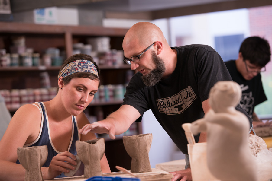 An instructor gives feedback to a WSU student during a pottery class.