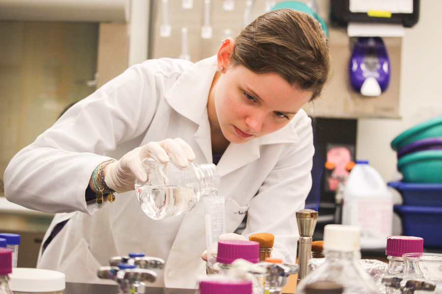 A WSU student pours chemicals into beakers in a lab.